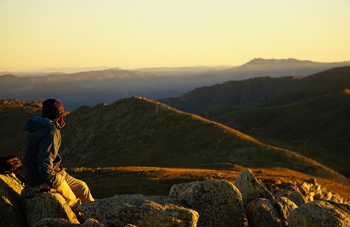 Hiker perched on the edge of a mountain in Kosciuszko National Park. Photo: James Crotty/DPE