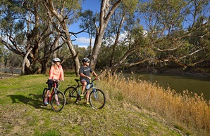 Two bike riders stop beside reed grass on the riverbank in Murrumbidgee Valley National Park. Photo: Gavin Hansford/DPIE