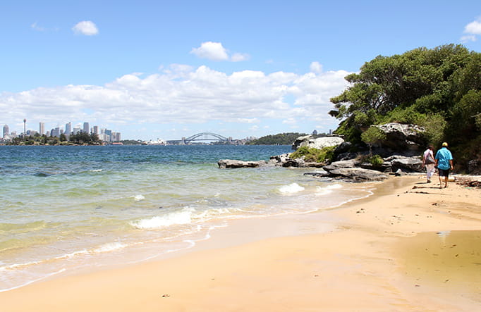 A man and woman walk along Milk Beach, accessed via Hermitage Foreshore walk in Sydney Harbour National Park. Photo; John Spencer/OEH