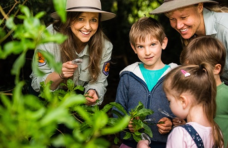 Photo of 2 Discovery Rangers with kids enjoying a tour in the bush. Credit © Louise Walpole/DCCEEW