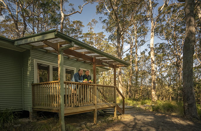 A couple stand on the balcony at Toms Cabin in New England National Park. Photo: John Spencer/OEH