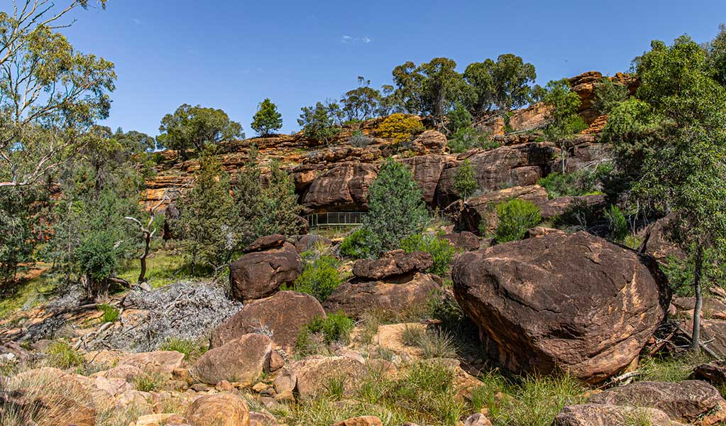 Rust coloured boulders surrounding Yapa (Mulgowan) Aboriginal art site walking track on the lands of the Ngemba and Paakandji Aboriginal people in Gundabooka National Park. Credit: Joshua J Smith &copy; DCCEEW