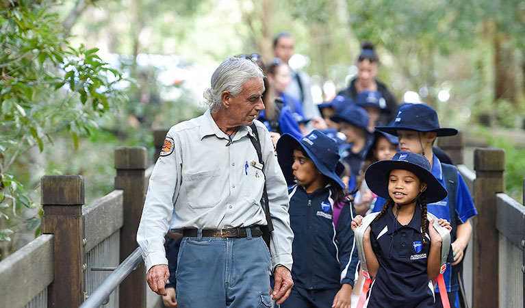 Students and an Aboriginal guide walking along a boardwalk on a school excursion in Glenrock State Conservation Area. Photo: Adam Hollingworth &copy; DPIE