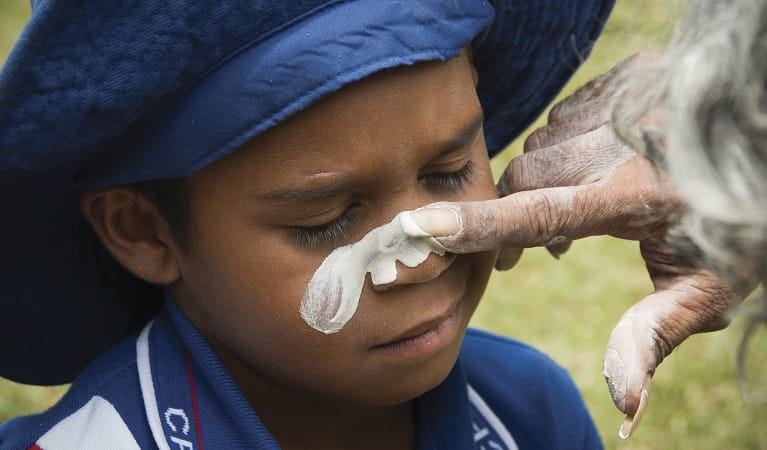 Painting a child’s face with ochre on a school excursion to Cape Byron State Conservation Area. Photo: David Young/OEH