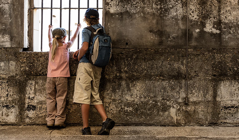 Image of kids peering through the bars in historic Trial Bay Gaol in Arakoon National Park. 