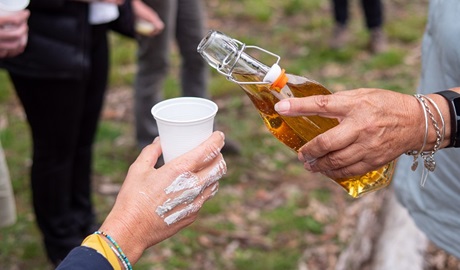 Person about to fill another person's cup with some lemon myrtle drink. Photo: Jessica Bray &copy; DPIE