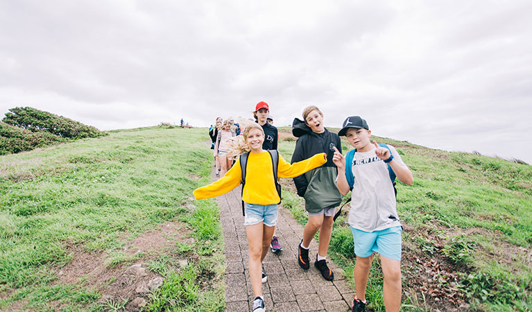 Students running down a hill on The rookery roundabout school excursion on Muttonbird Island Nature Reserve. Photo: And the Trees Photography &copy; DPIE