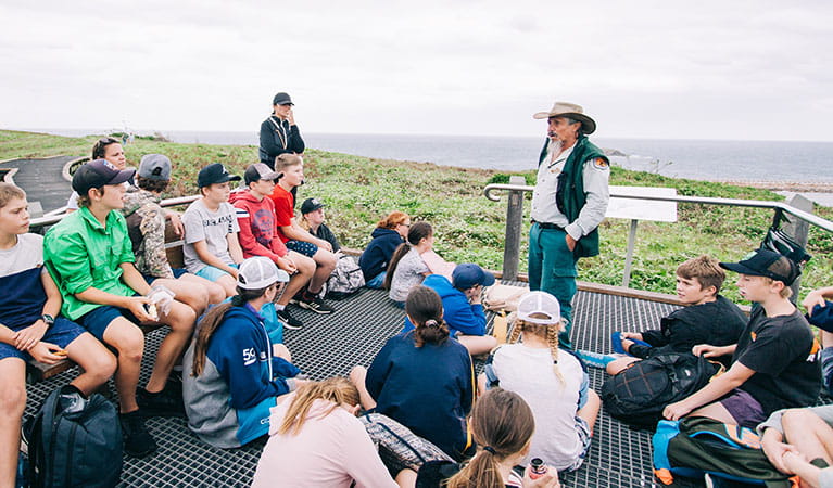 A group of students listening to an NPWS guide on The rookery roundabout school excursion in Muttonbird Island Nature Reserve. Photo: And the Trees Photography &copy; DPIE