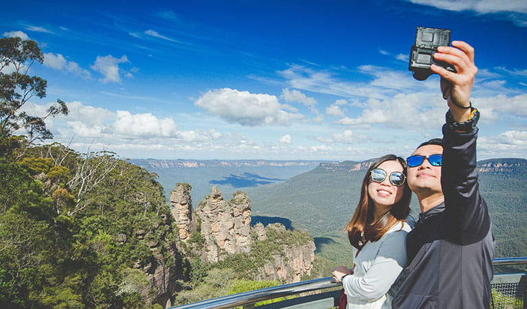 A couple take a selfie with the Three Sisters in the background on a tour with Activity Tours Australia in Blue Mountains National Park. Photo: Luke Thurlby &copy; Activity Tours Australia