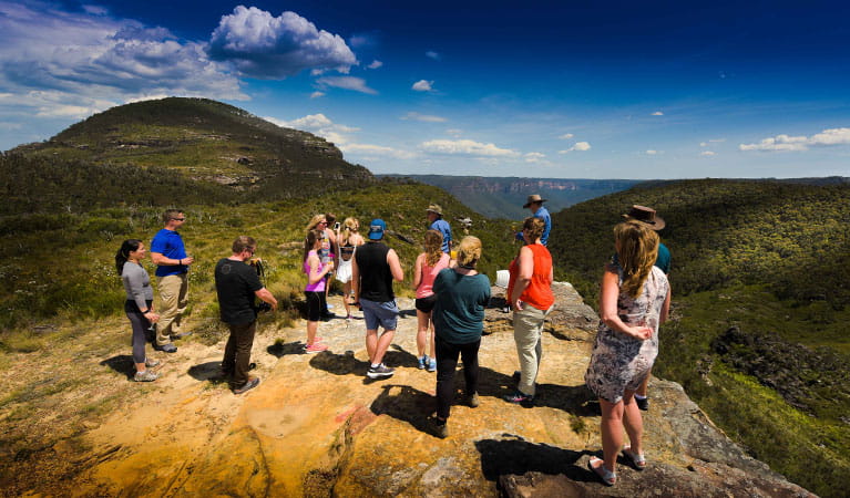 Tour guests gather at a rocky lookout platform with sweeping valley and mountain views. Photo &copy; AEA Luxury Tours