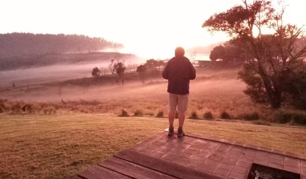 A hiker watching the sunrise from the deck of a heritage hut along the Green Gully track on a guided hike with Aussie Hike or Bike in Oxley Wild Rivers National Park. Photo: Judie Bowman &copy; Aussie Hike or Bike