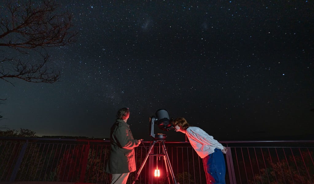 Stargazers examine bright night sky through large telescope. Photo &copy; Tourism Australia