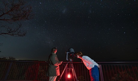 Stargazers examine bright night sky through large telescope. Photo &copy; Tourism Australia