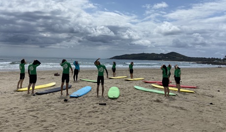 Group of surfers in wetsuits stretching on the beach. Photo: &copy; Jayme Edwards