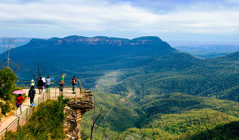  Members of a tour group stand on the rock shelf of a lookout with sweeping views of Blue Mountains National Park. Photo &copy; Colourful Trips