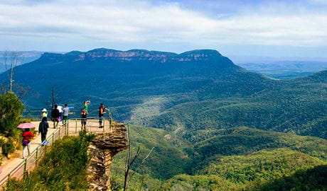  Members of a tour group stand on the rock shelf of a lookout with sweeping views of Blue Mountains National Park. Photo &copy; Colourful Trips