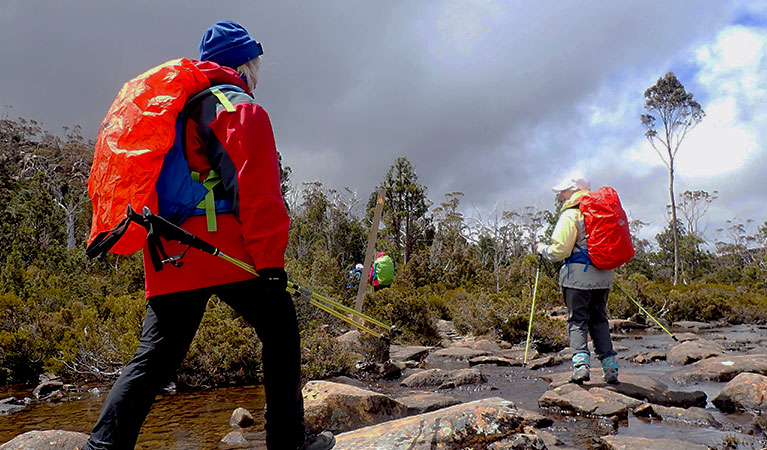 Women trek along a rocky river bed using hiking poles. Photo credit: Michele Michel &copy; Diamonds in the Rough Adventures  