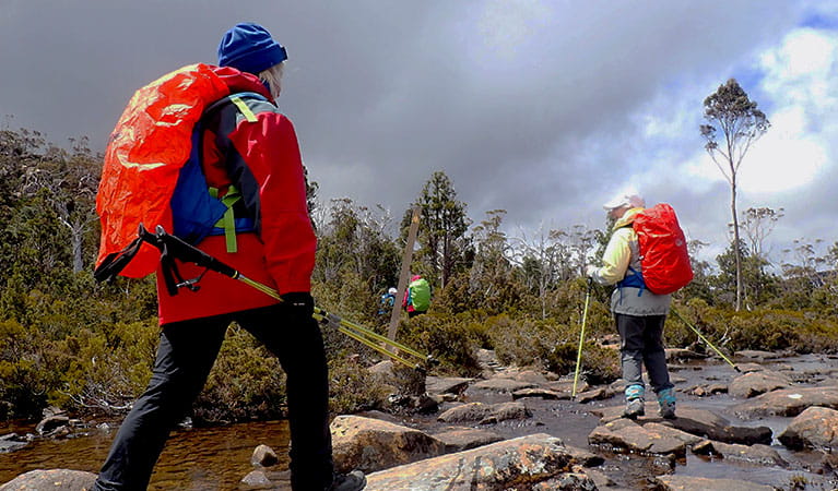 Women trek along a rocky river bed using hiking poles. Photo credit: Michele Michel &copy; Diamonds in the Rough Adventures  
