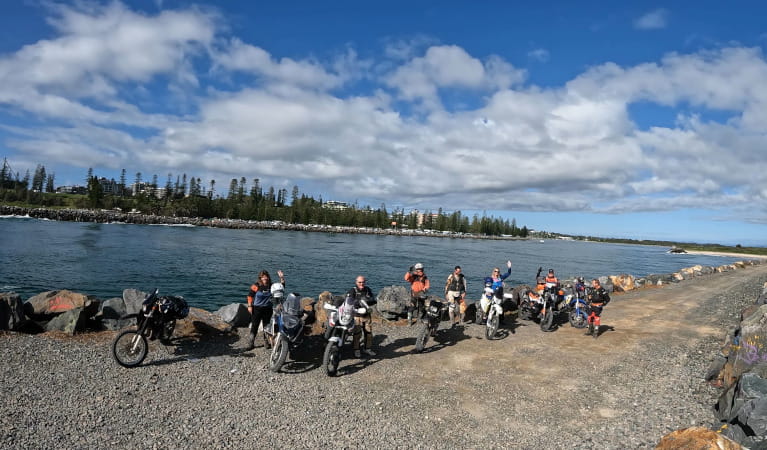 Group of people with motorcycles on Port Macquarie seawall. Photo &copy; Endeavour Motorcycle Tours
