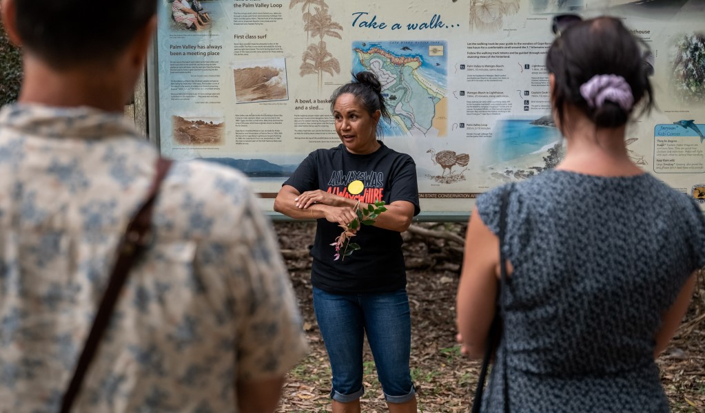 An Aboriginal guide from Explore Byron Bay displaying a native plant to visitors on a guided tour in Walgun Cape Byron State Conservation Area. Photo: Sam Clarke &copy; Explore Byron Bay