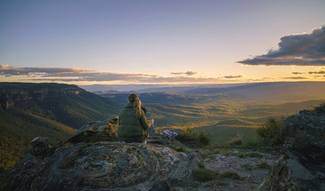 Visitor sits peacefully on a large rock, gazing out over the vast, panoramic expanse of the Blue Mountains. Credit: FeelGood! Nature Tours &copy; FeelGood! Nature Tours