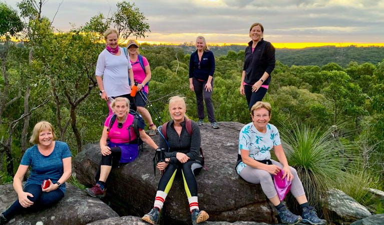 A group of women on a Fittrek training session gather at twilight next to a rocky outcrop with wide views over park landscape. Photo &copy;  Roz Warne