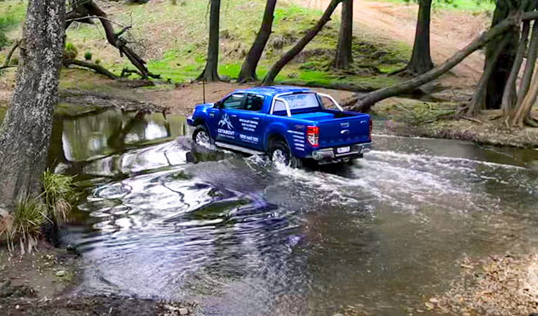 A blue 4WD vehicle makes a river crossing in bushland. Photo &copy; Getabout 4WD Adventures