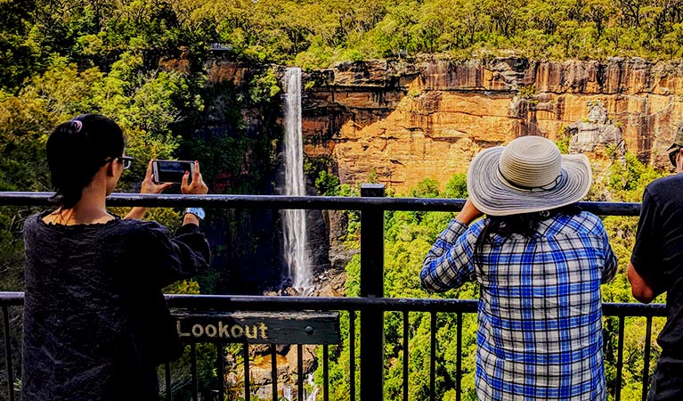 Women photograph a waterfall cascading down a cliff face.  Photo: Steve Nomchong &copy; Local Travel Planner