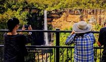 Women photograph a waterfall cascading down a cliff face.  Photo: Steve Nomchong &copy; Local Travel Planner