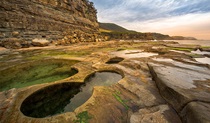 Aerial view of rock shelf with Figure Eight Pools, and rugged coastline in the distance. Photo credit: John Spencer &copy; DPIE