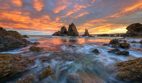 Rocky edge of ocean with orange sunset in background. Photo &copy; Mark Gray Gallery & Photography Tours