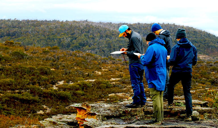 A group of hikers studies navigational aids in rugged terrain in Blue Mountains National Park. Photo credit: Ashley Burke &copy; MountainSphere Adventures and Education
