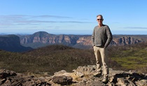 Your tour guide from One Guide Tours atop a lookout with mountains in the distance in Blue Mountains National Park. Photo: Thomas Walmsler &copy; One Guide Tours. 