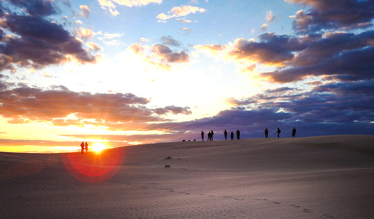 A group of tour guests take in a spectacular sunset sky in Mungo National Park. Photo credit: German Ugarte &copy; Outback Geo Adventures