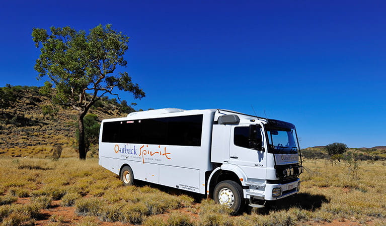 Outback Spirit tour bus set in an outback landscape of dry shrubland and hills. Photo credit: Steve Strike &copy; Outback Spirit