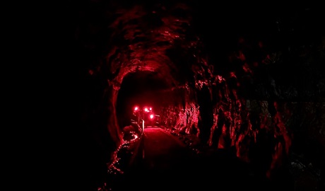 A group of people with red light torches walking through the dark at Glow Worm Tunnel in Wollemi National Park. Photo: Blake North &copy; Red Lantern Tours