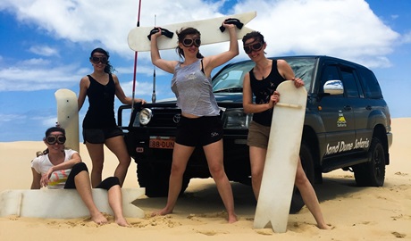 A tour group standing in front of a 4WD with their sandboards. Credit: Andrew Hay &copy; Sand Dune Safaris