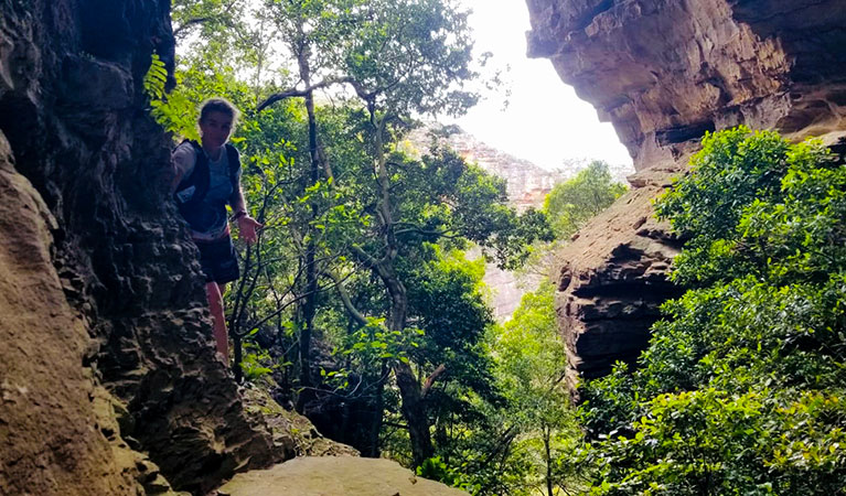 A woman on a guided tour with Serotonin Running at a cave entrance in Blue Mountains National Park. Photo: Elouise Peach &copy; Serotonin Running