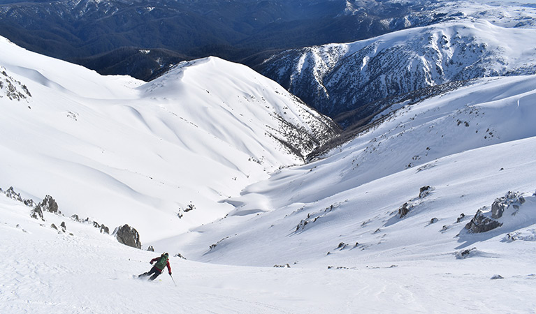 A lone skier descends into a snow-covered mountain valley. Photo credit: Rohan Kennedy &copy; Snowy Mountains Backcountry