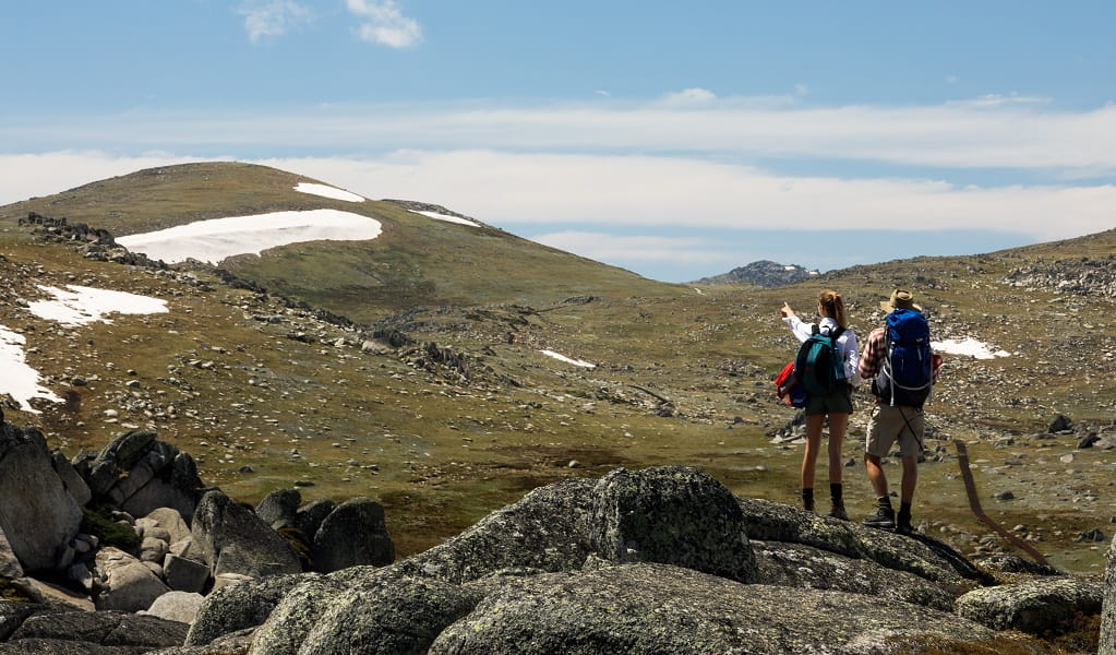 Two walkers pause on a rocky outcrop to admire the view on their way to Mount Kosciuszko Summit. Credit: Aedan O’Donnell &copy; Thredbo Resort