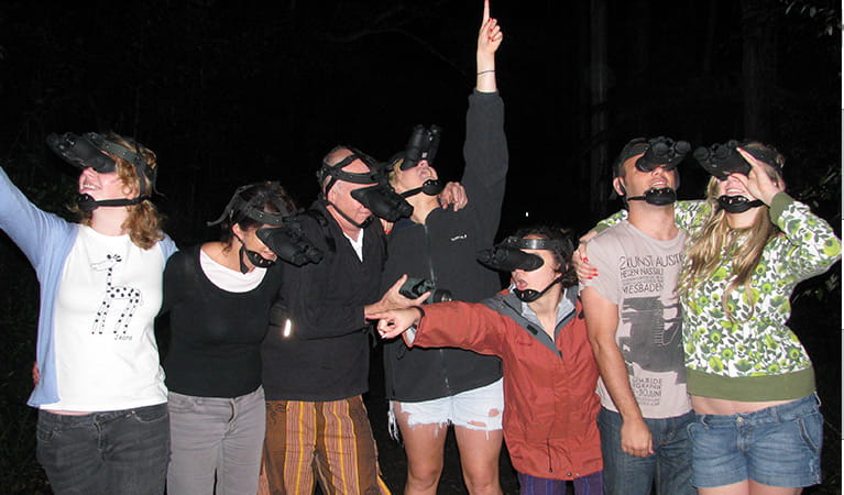A group of 7 guided tour participants wearing night vision goggles in the dark. Photo credit: Wendy Bithell &copy; Vision Walks Eco Tours
