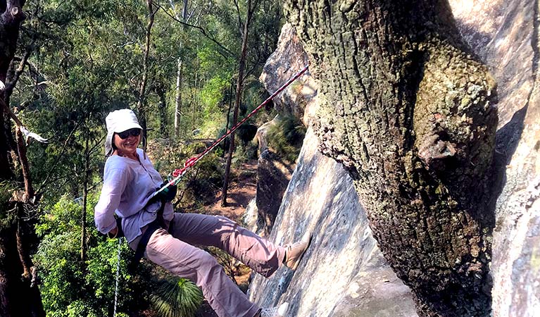A woman abseils down a cliff surrounded by bushland in Watagans National Park. Photo &copy; Walking Rivers