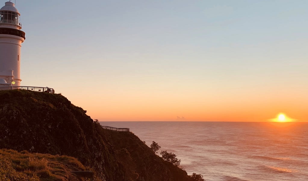 View of the sun rising behind Cape Byron Lighthouse on a Wander Byron tour. Photo: Chris Mills &copy; Wander Byron