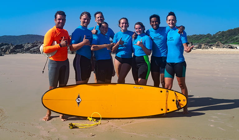 A group of surfers and their instructor pose with a surfboard on the beach. Photo credit: Annemieke Yperlaan &copy; Waves Campground