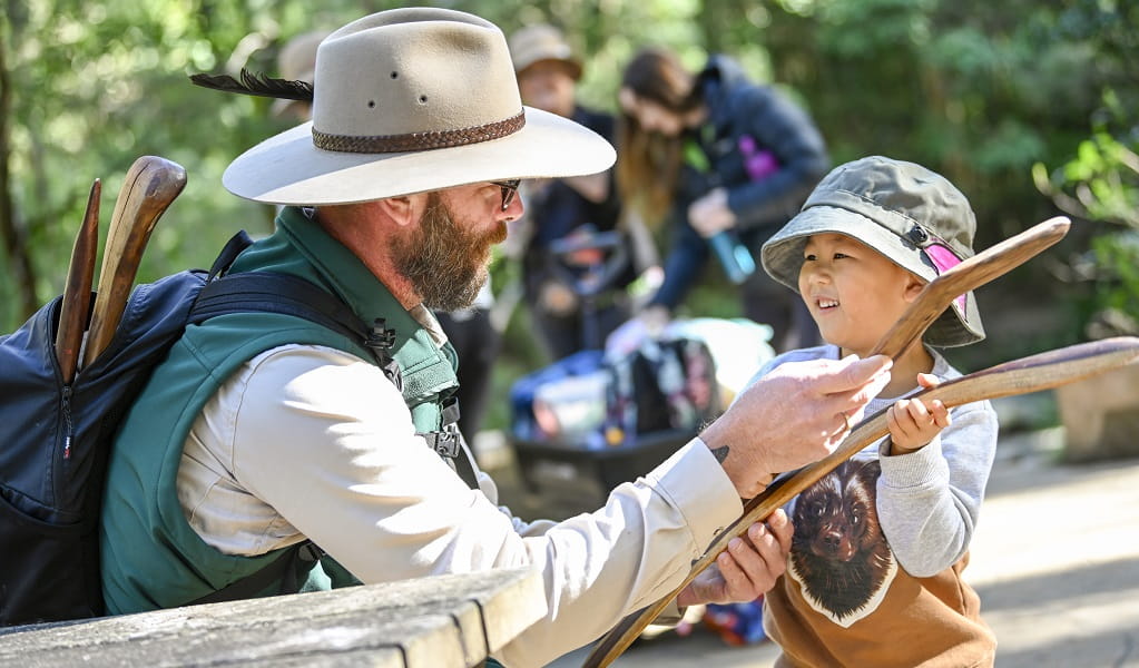 A NPWS Aboriginal Discovery ranger teaching a child abut traditional tools. Photo: Adam Hollingworth/DPE