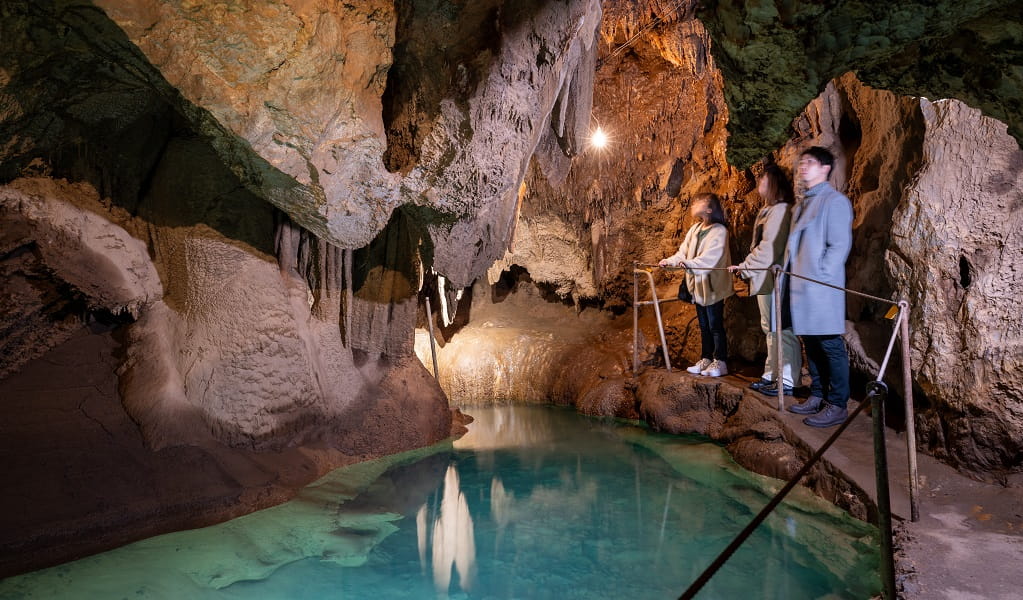 A group of visitors admire a pool of water in a limestone cave at Jenolan Caves. Photo: Jenolan Caves &copy; DPE