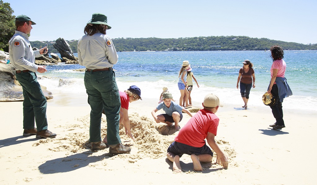NPWS Discovery rangers and a group of kids playing in the sand at the beach. Photo: Rosie Nicolai/OEH