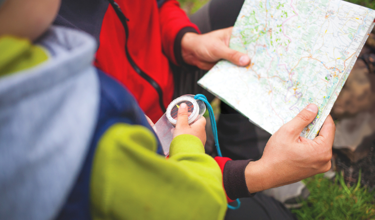 Child holding a compass and reading a map. Photo: Zhukovvvlad/Shutterstock