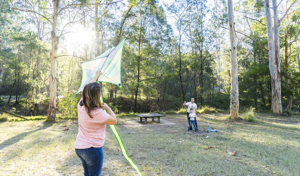 A woman and man helping a child to fly a kite. Photo: Simone Cottrell &copy; DPE