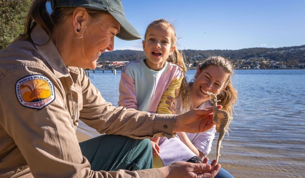 An NPWS ranger shows a young girl and her mother a seahorse. Photo: David Rogers &copy; DCCEEW